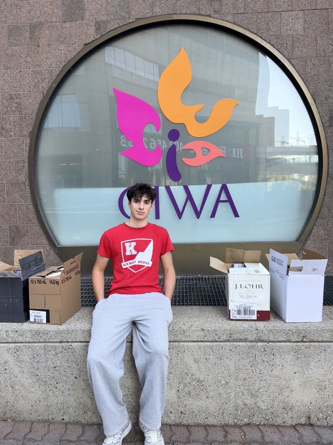 Jeo Metelitsa sitting outside CIWA's office in Calgary with boxes of donated books beside him